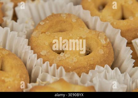 Gros plan de biscuits danois au beurre en forme de bretzel recouverts de sucre, présentés dans des doublures en papier blanc Banque D'Images