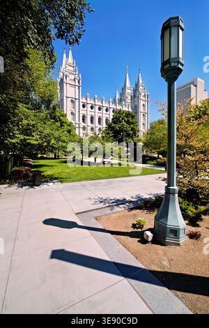 Salt Lake Temple se dresse haut parmi les arbres verts sous le ciel bleu. Les gens apprécient le parc autour du temple pendant la journée. Banque D'Images