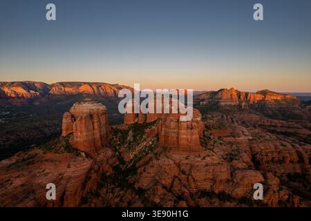 Lumière dorée illuminant les buttes de roche rouge et mesas de Sedona Arizona au coucher du soleil avec le ciel spectaculaire et les montagnes lointaines. Banque D'Images