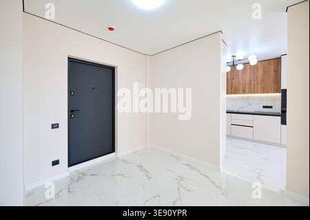 Couloir résidentiel contemporain avec carrelage poli, portes ouvertes multiples et murs neutres doux. Intérieur d'appartement élégant, rénovation élégante et concept immobilier Banque D'Images