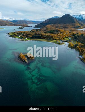 Vue aérienne de Hamn i Senja avec des eaux côtières turquoises, feuillage d'automne et montagnes enneigées à Skaland, Troms, Norvège. Banque D'Images