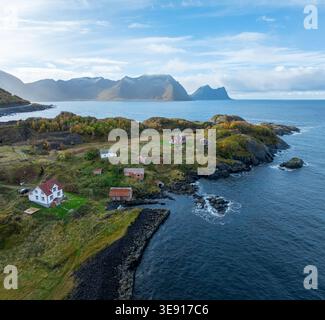 Vue aérienne du village côtier de Hamn i Senja avec des maisons traditionnelles rouges et blanches le long du rivage rocheux et des montagnes à Skaland, Troms, No Banque D'Images