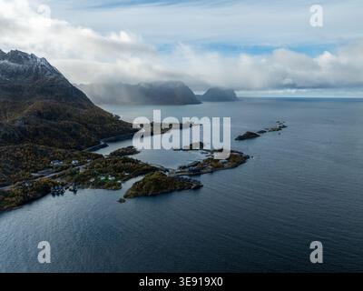 Vue aérienne de Hamn i Senja Resort niché entre les montagnes escarpées et la mer bleu profond sous un ciel nuageux à Skaland, Troms, Norvège. Banque D'Images