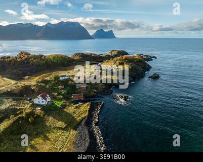 Vue aérienne de Hamn i Senja avec des maisons traditionnelles sur une côte rocheuse avec des montagnes et la mer bleue sous un ciel nuageux Skaland, Troms, Norwa Banque D'Images