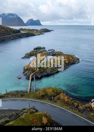 Vue aérienne de la station Hamn i Senja sur une petite île avec feuillage d'automne, eaux turquoises et montagnes escarpées à Skaland, Troms, Norvège. Banque D'Images