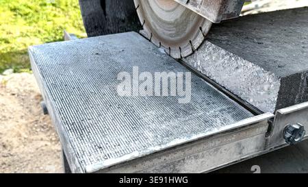 Concrete cutting machine with diamond blade positioned over a slab, showcasing precision cutting tools and measurement markings on the metal guide Banque D'Images