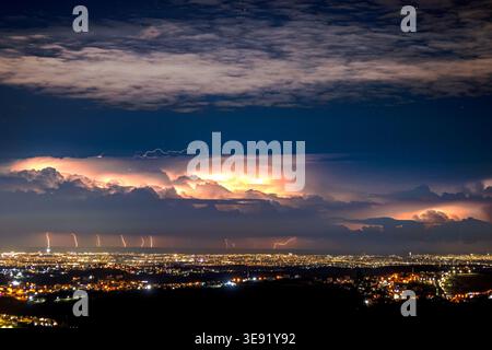 Plusieurs éclairs spectaculaires sur les lumières de la ville - paysage de tempête nocturne dramatique. Banque D'Images