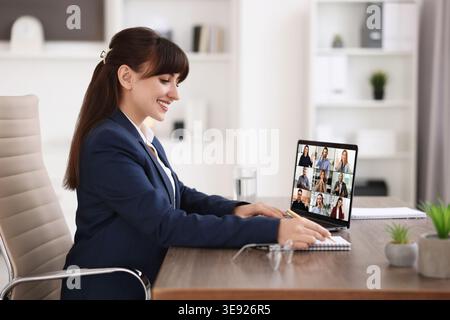 Femme d'affaires ayant chat vidéo avec ses collègues via ordinateur portable au bureau Banque D'Images