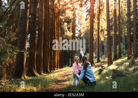 Mère et fille explorant la forêt, profitant de la nature sauvage regardant les arbres. Banque D'Images