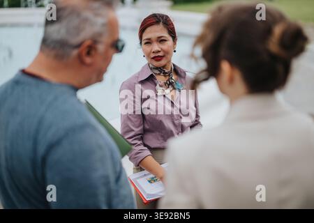 Collègues d'affaires discutant des documents à l'extérieur avec une femme professionnelle menant la conversation Banque D'Images