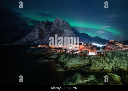Les aurores boréales dansent sur le village de pêcheurs traditionnel de Hamnøy dans les îles Lofoten, en Norvège, sous un ciel étoilé en hiver Banque D'Images
