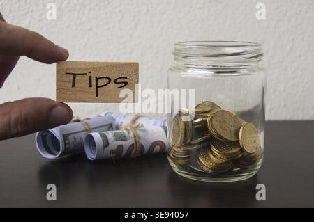 Main tenant bloc en bois avec texte de pointes. Avec des pièces d'or et des billets de banque de fond Banque D'Images