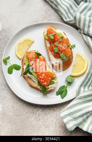 Deux mini-sandwichs sains avec saumon fumé, avocat, fromage à la crème et pousses de pois dans une assiette Banque D'Images