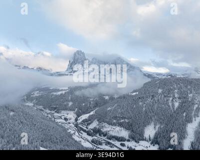 Vue aérienne de la chaîne de montagnes enneigée des Dolomites et des forêts denses de pins surplombant la vallée d'Ortisei, Trentin-Haut-Adige, Italie. Banque D'Images