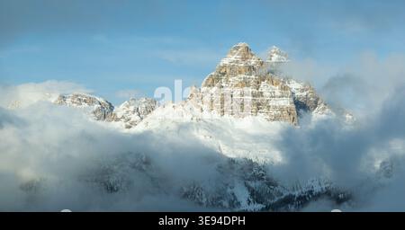 Vue aérienne des sommets enneigés des Dolomites s'élevant au-dessus d'une épaisse couche de nuages blancs sous un ciel bleu clair à Rocca Pietore, Vénétie, Ita Banque D'Images