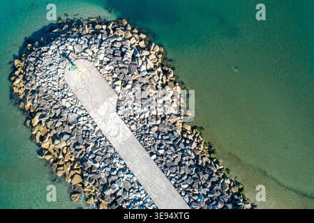 Vue aérienne du brise-lames en béton dans l'eau bleue de l'océan Banque D'Images