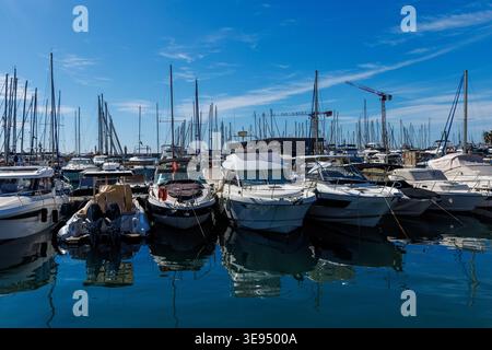 De nombreux bateaux à moteur modernes blancs et yachts à voile amarrés dans l'eau bleue calme d'une marina méditerranéenne. Banque D'Images