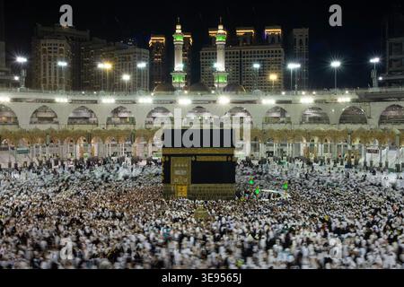 Une grande foule de gens se réunit autour de la Kaaba dans la Grande Mosquée, exécutant le rituel Tawaf la nuit. Banque D'Images