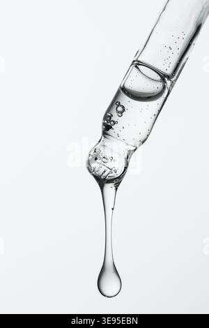 Pipette en verre macro avec goutte de sérum brillant Banque D'Images