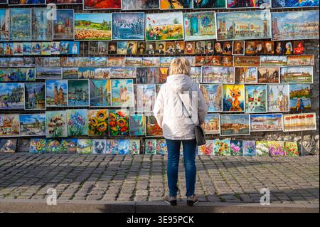 Cracovie, Pologne - 10 avril 2026 : personne se tient devant un mur couvert de diverses œuvres d'art à Cracovie, Pologne. Banque D'Images