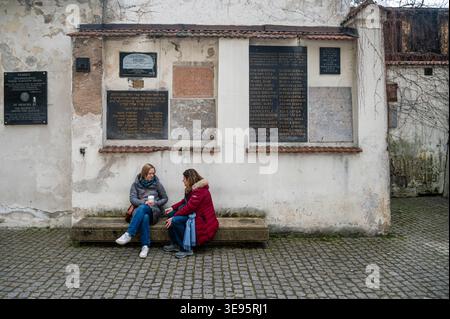 Cracovie, Pologne - 12 avril 2026 : deux femmes s'assoient et discutent près de monuments commémoratifs juifs à Kazimierz, Cracovie, Pologne. Banque D'Images