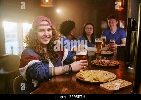 Portrait d'une adolescente appréciant Sports Bar se réunissant avec des amis Banque D'Images