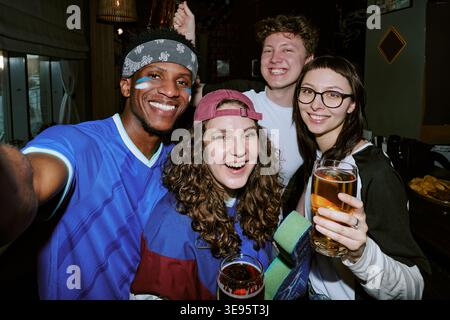 Portrait de divers amis célébrant la victoire sportive dans un pub Banque D'Images