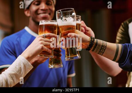 Des amis divers grillent de la bière lors d'un rassemblement social décontracté Banque D'Images