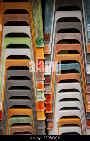 Gros plan détail abstrait de chaises empilables en plastique colorées et altérées. Banque D'Images