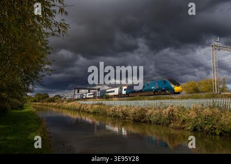 Train Avanti Pendolino sous de sombres nuages orageux le long du canal d'Oxford, Ansty, Shilton Warwickshire Banque D'Images