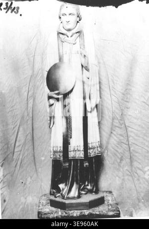 La statue d'un saint prêtre, photographiée vers 1900, est de la collection de Kunstwerkplaatsen Cuypers & Co. La photographie montre une image détaillée d'un prêtre saint, avec une corde autour du cou et un disque dans sa main droite. Banque D'Images