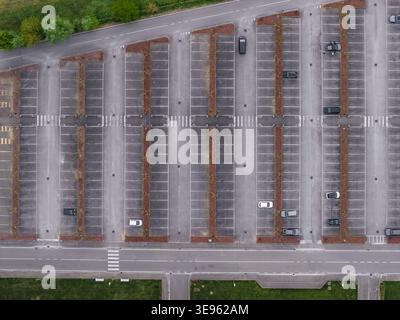 Vue aérienne d'un grand parking extérieur avec plusieurs voitures garées dans des stands balisés et une route avec un passage à Leccio, Toscane, Italie. Banque D'Images