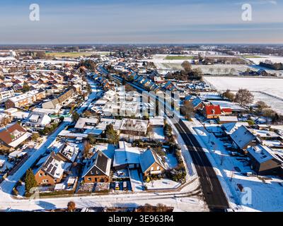Vue aérienne d'une ville européenne tranquille après une chute de neige. L'image montre des toits enneigés, des routes asphaltées propres et des champs ensoleillés s'étendant jusqu'au Banque D'Images