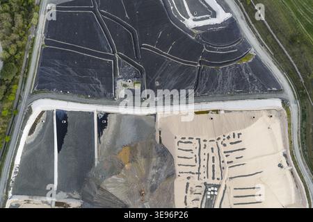 Vue aérienne d'un site de gestion des déchets industriels avec de grands revêtements de protection noirs et bruns et des zones d'excavation à Pomarance, Toscane, Italie. Banque D'Images