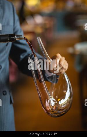 Sommelier versant du vin rouge dans une carafe en verre Banque D'Images