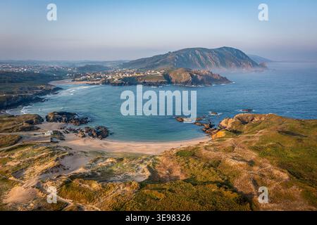 Vue aérienne du village côtier, plage de sable et falaises rocheuses au lever du soleil sur la baie, Praia Da Cristina, Galice, Espagne Banque D'Images