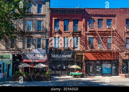 New York, NY, États-Unis - Une rangée de bâtiments historiques en briques avec des espaces commerciaux au rez-de-chaussée est vue le long d'une rue à Harlem Banque D'Images