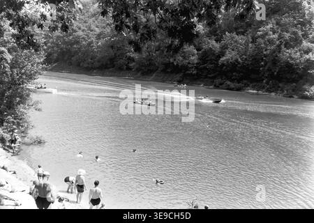 Historique 1956 vue d'archives de Slavyanogorsk (aujourd'hui Sviatohirsk) montrant les loisirs en plein air sur la pittoresque rivière Siverskyi Donets. La scène capture les habitants nageant dans l'eau calme et se relaxant sur la plage de sable tandis que plusieurs bateaux à rames et bateaux à moteur en bois glissent le long des rives boisées. Ce paysage nostalgique du milieu du XXe siècle met en valeur la beauté naturelle et la culture vibrante des vacances d'été de l'ère soviétique, préservant l'environnement historique et la vie quotidienne de la région, reflétant le Donbass paisible. Banque D'Images