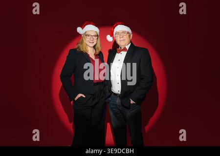 Portrait de l'équipe de noël festive heureuse d'affaires, isolé sur fond de lumière rouge. Banque D'Images