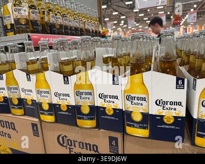 Moscou, Russie - 01 avril 2026 : bouteilles de bière Corona Extra exposées en paquets sur une étagère dans un magasin de détail avec des acheteurs de fond floue Banque D'Images