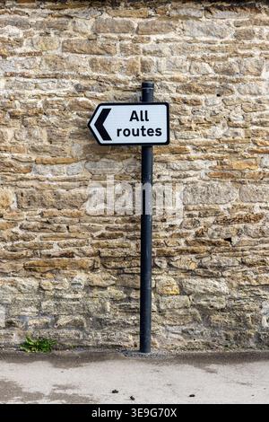 Flèche noire et blanche tous les itinéraires panneau de circulation indiquant la direction du voyage, Lacock Village, Wiltshire, Angleterre, Royaume-Uni Banque D'Images