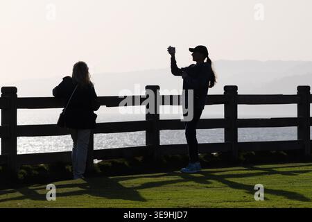 Visiteurs silhouettés photographiant la côte depuis une falaise à Santa Monica, Californie, États-Unis Banque D'Images