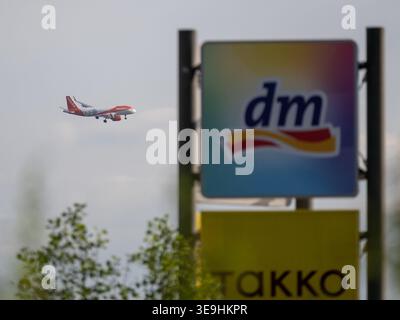 Ein EasyJet Airbus A320neo mit ausgefahrenem Fahrwerk überfliegt verschwommene Werbeschilder von dm und Takko. Foto : Eibner-Pressefoto/Thomas Hess Banque D'Images