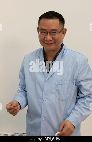 Médecin masculin asiatique souriant en manteau médical bleu clair tenant une aiguille d'acupuncture, portrait en clinique, médecine traditionnelle chinoise. Banque D'Images
