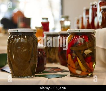 Des bocaux en verre remplis de légumes marinés, dont des poivrons et des concombres, disposés sur une table, présentent des spécialités culinaires arméniennes traditionnelles Banque D'Images