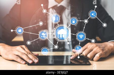 Un homme d'affaires en costume interagit avec une tablette, entouré d'icônes de cloud computing, symbolisant la technologie moderne et les solutions de connectivité réseau Banque D'Images