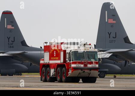 Un camion de sauvetage et de lutte contre l'incendie de l'aérodrome P23 avec l'USAF à Yokota, base aérienne devant un avion C130J Super Hercules stationné, Tokyo, Japon. Banque D'Images