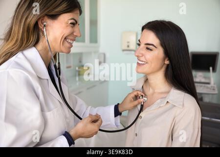 Une jeune femme infirmière ou cardiologue en manteau examine la patiente Banque D'Images