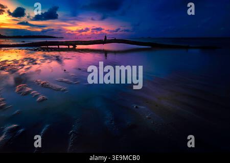 Vue sur le coucher de soleil sur la plage à marée basse Banque D'Images