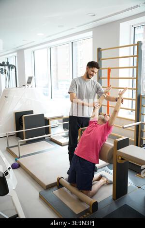 Physiothérapeute guidant l'homme âgé dans l'exercice de rééducation Banque D'Images